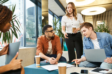 A diverse group of colleagues engaged in a collaborative work session, seated around a table, each focused on their laptops.
