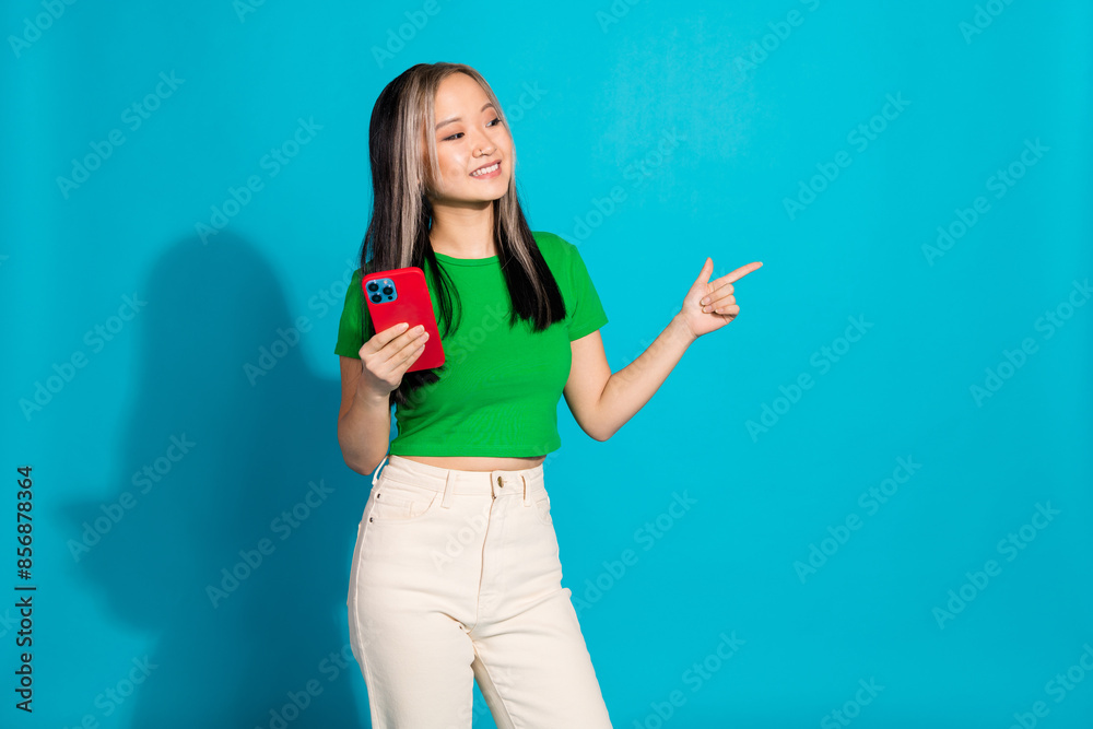 Wall mural photo of nice young girl smart phone direct finger empty space wear green t-shirt isolated on teal c