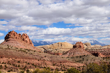 A stunning panoramic view of Capitol Reef National Park's Waterpocket Fold in Utah, showcasing the scenic rocky landscape under a bright blue sky with clouds. Taken on the Burr Trail Road - USA