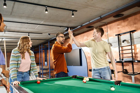 A group of colleagues from a coworking space gather around a pool table, enjoying a break and building team camaraderie. - Powered by Adobe