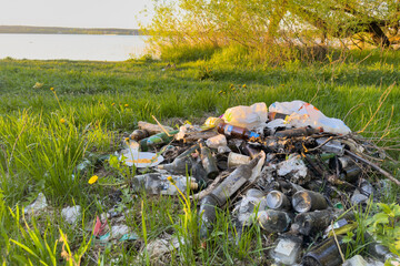 Garbage dump on beach at lake. People throw garbage near lake in nature. Trash at camping resort. Pile of rubbish in nature. Environmental pollution and ecology. Illegal dumping of Garbage near river