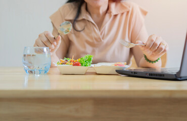 Cropped shot of female nutritionist with healthy food working on notebook at table in office.