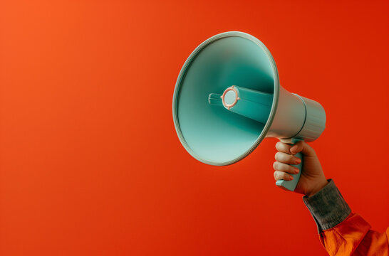 Close-up of a hand holding a megaphone on a vibrant red background, highlighting communication and announcements.