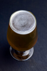light golden beer in a glass glass on a black background