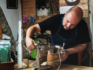 Shoemaker placing shoes on lasts to repair and shape them. Trades, small business.