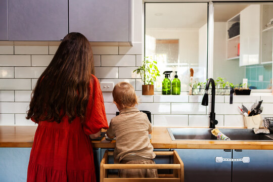 mother and young son cooking together in kitchen doing dinner prep