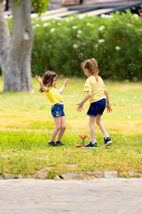 Cute little sisters having fun with water at the park fountain. Girls playing water games outdoors on a hot day. Summer activities for young children.