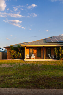 Suburban house with sunset light on bricks and solar panels installed on roof