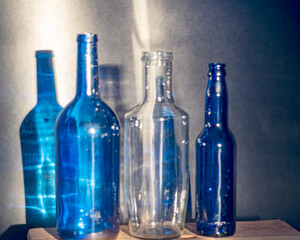 Still life with blue glass bottles, quiet shadows in the background, soft evening light
