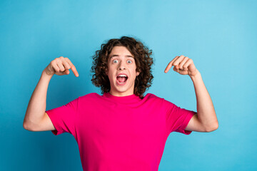 Photo of astonished guy with wavy hair earrings dressed pink shirt indicating at himself staring...