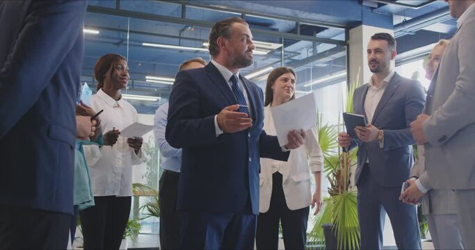 Positive chief leading a meeting or training session for a multinational group of business people in the office. Engaging in a conversation to coach and guide the team towards success.