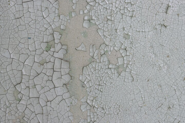 Peeling paint on the wall. Old concrete wall with cracked flaking paint. Weathered rough painted surface with patterns of cracks and peeling. High resolution texture for background and design. Closeup
