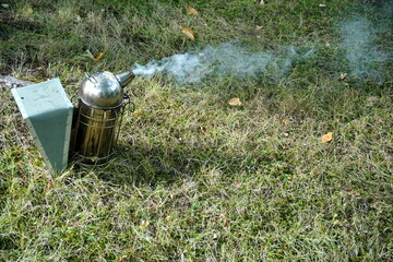 Close up of a beekeepers smoking equipment with smoke and fire coming out of the nozzle


