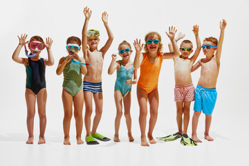 Group of little children ready for swim, having fun together in swimwear and diving equipment against white studio background. Concept of hot summer holidays, vacation, camps, recreation.