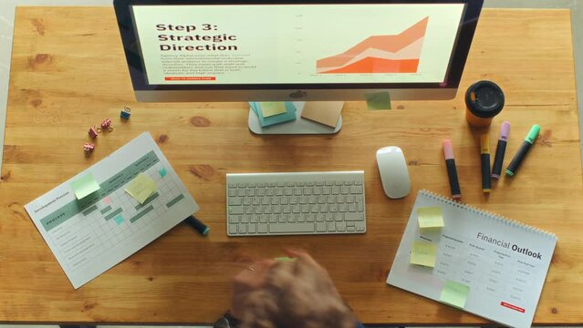 Professional businesswoman typing on computer keyboard, highlighting text on papers and writing sticky notes as working on strategic plan at desk in the ofice. Time lapse, directly above view