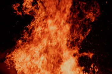 Close-up view of a large fire with intense flames against a dark background.