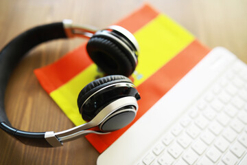 Naklejka premium Headphones and Spanish Flag Next to Keyboard - Modern Technology and Culture Concept