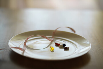 Weight Loss Concept with Pills and Measuring Tape on Empty Plate