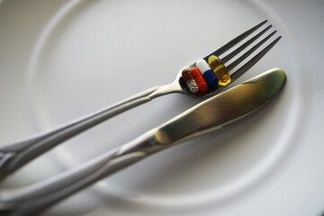 Fork with Multicolored Pills on Plate Symbolizing Medicine as Food Concept