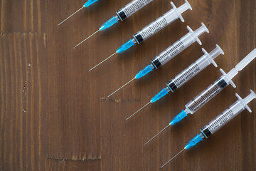 Row of Medical Syringes on Wooden Surface - Healthcare, Injection, Vaccination, Medical Equipment,...