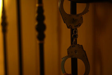 Close-Up of Handcuffs on Jail Bars in Dimly Lit Cell Highlighting Judicial System and Incarceration