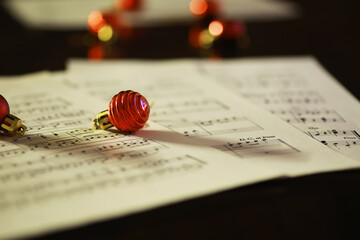 Festive Red Christmas Ornament on Music Sheets with Soft Focus Holiday Lights