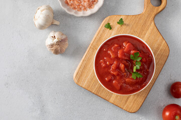 Canned whole peeled tomatoes with juice and parsley on table. Copy space