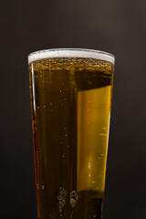 light golden beer in a glass glass on a black background
