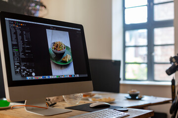 Food photography production set showing computer, keyboard, camera and tripod. Bowl of noodles.