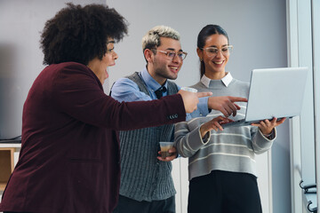 three people in the office looking at the laptop surprised by the economic profits of the month