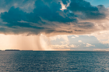 Fantastic stormy sea view of dark overcast sky clouds. Dramatic picturesque morning sunrise scene. Tropical seascape beautiful calm waves soft sunlight and heavy rain. Summer island sea surface