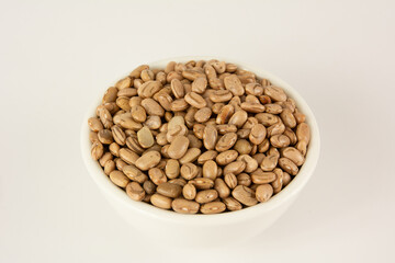 Tigela de porcelana branca cheias de feijao cru em fundo branco