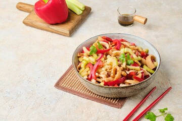 Salad from squid, sweet pepper and celery in the Asian style in a ceramic bowl on a light concrete background. Receptam -products, squid.