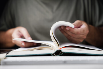 Closeup man flips the book pages to search the information, fact check, find a reference text, or...