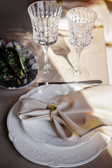 Festive table setting. Plates and cutlery with gray decorative textile and white napkin on white plate.