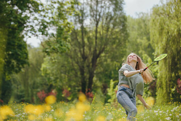 A young man and his girlfriend spend time together playing badminton on a lawn in a park.