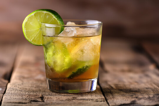 mojito cocktail on wooden table, An authentic image of a Brazilian Caipirinha, showcasing the classic cocktail in a traditional glass with a lime wedge garnish