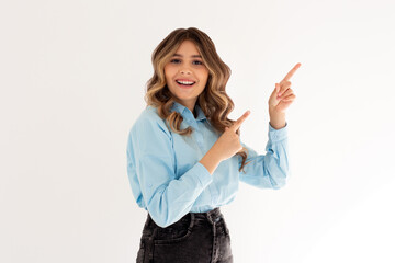 Young confident woman showing logo on empty space. Smiling girl inviting or advertising promo deal, pointing fingers right and looking at camera, white background.