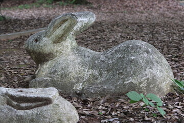An old stone statue of a rabbit with a constricted waist in the park