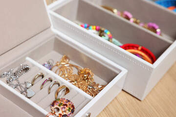 Jewelry boxes with stylish bracelets and other accessories on wooden table, closeup