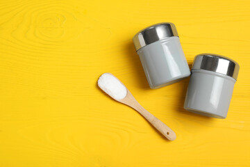 Spice shakers with salt on yellow wooden table, flat lay. Space for text