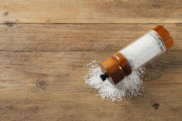 Salt shaker on wooden table, top view. Space for text