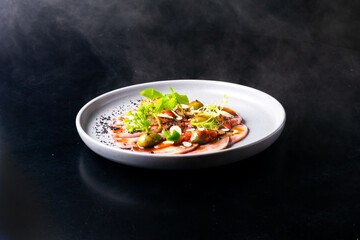 Beef tongue with sauce and vegetables on a white plate