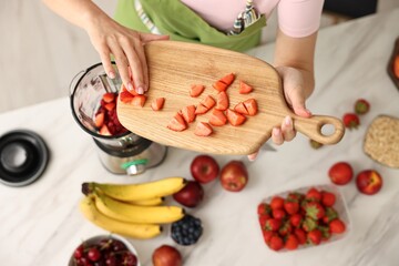 Woman making delicious smoothie with blender at white marble table in kitchen, above view