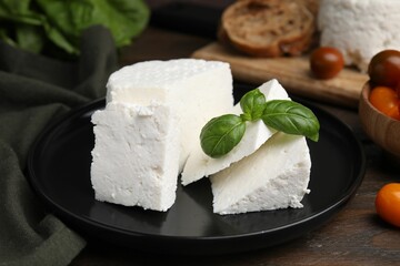 Fresh ricotta (cream cheese) and basil on wooden table, closeup
