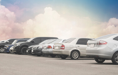 Cars parking in a row in stock background. Vehicle transportation trip inventory merchandise. Car parked in large asphalt parking lot with white cloud and blue sky background. Outdoor parking lot