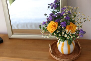 Vase with beautiful flowers on wooden table indoors, space for text