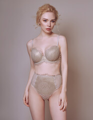 Beautiful blonde woman with a perfect body in lingerie with petals in the background. Studio spring tender concept.