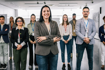 Portrait of  Hispanic woman CEO standing  with her hands crossed in front of her colleagues.