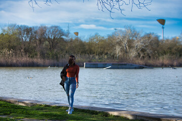 Young, beautiful brunette woman, with short hair and jeans and orange shirt with jacket over her...
